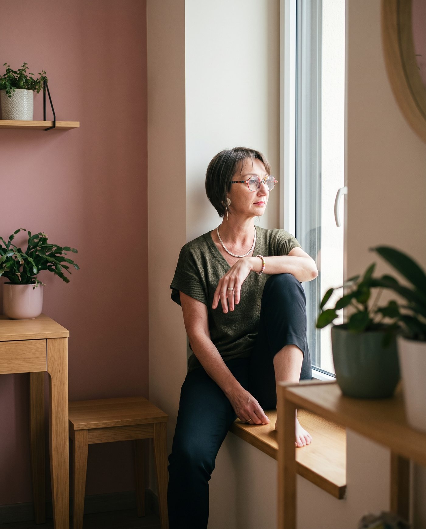 Émilie Haras assise sur un rebord de fenêtre, le regard vers l'extérieur