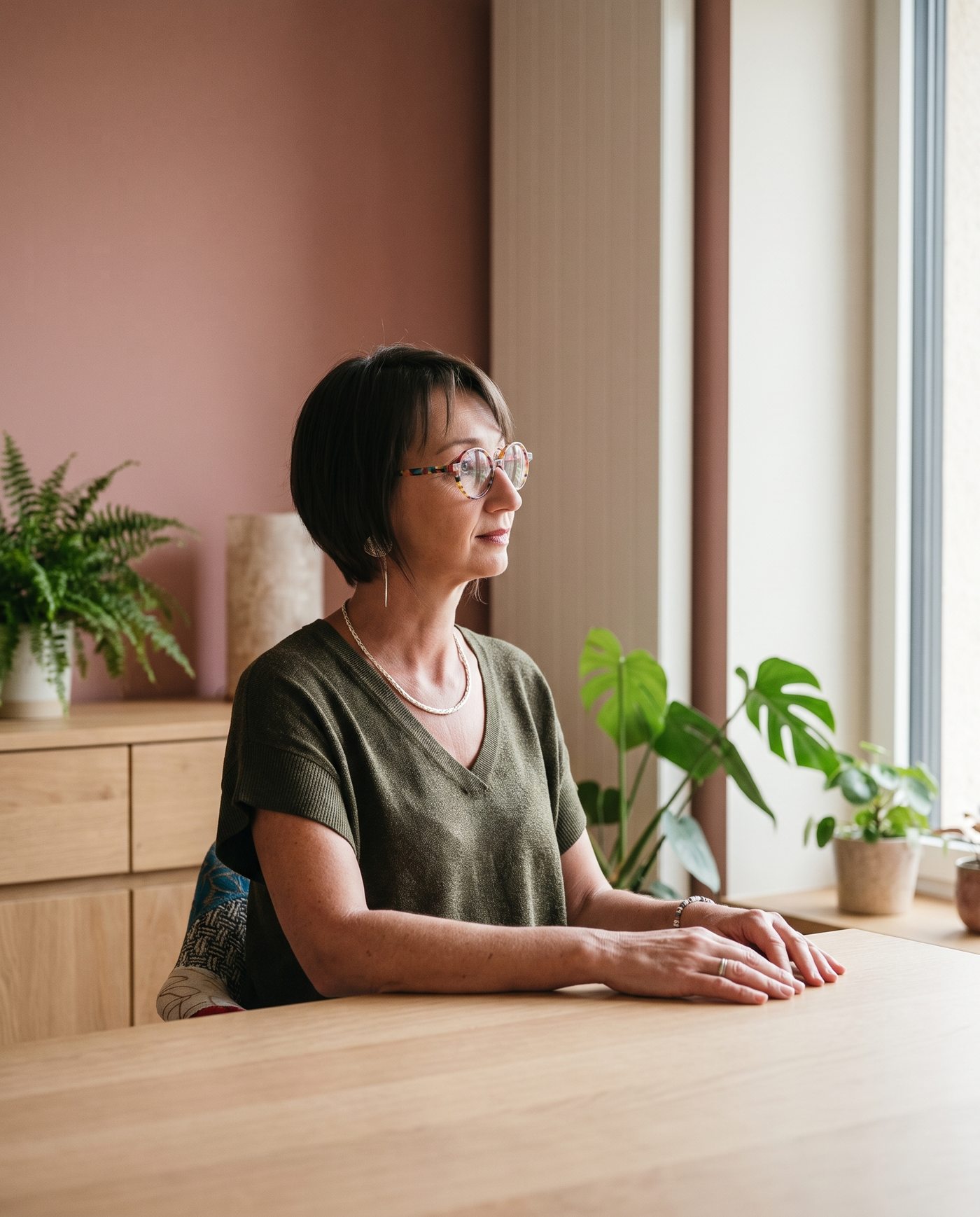 Émilie Haras assise à une table près d'une fenêtre, le regard tourné vers l'extérieur