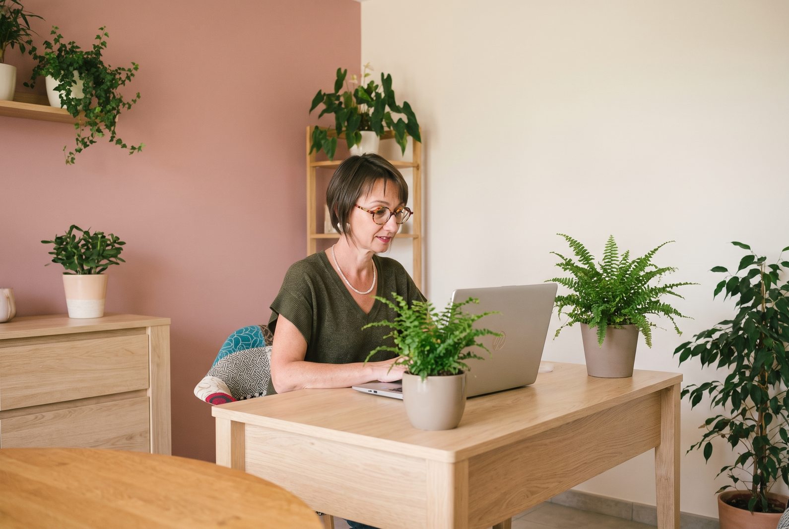 Émilie Haras devant un ordinateur portable ouvert, une plante verte à côté