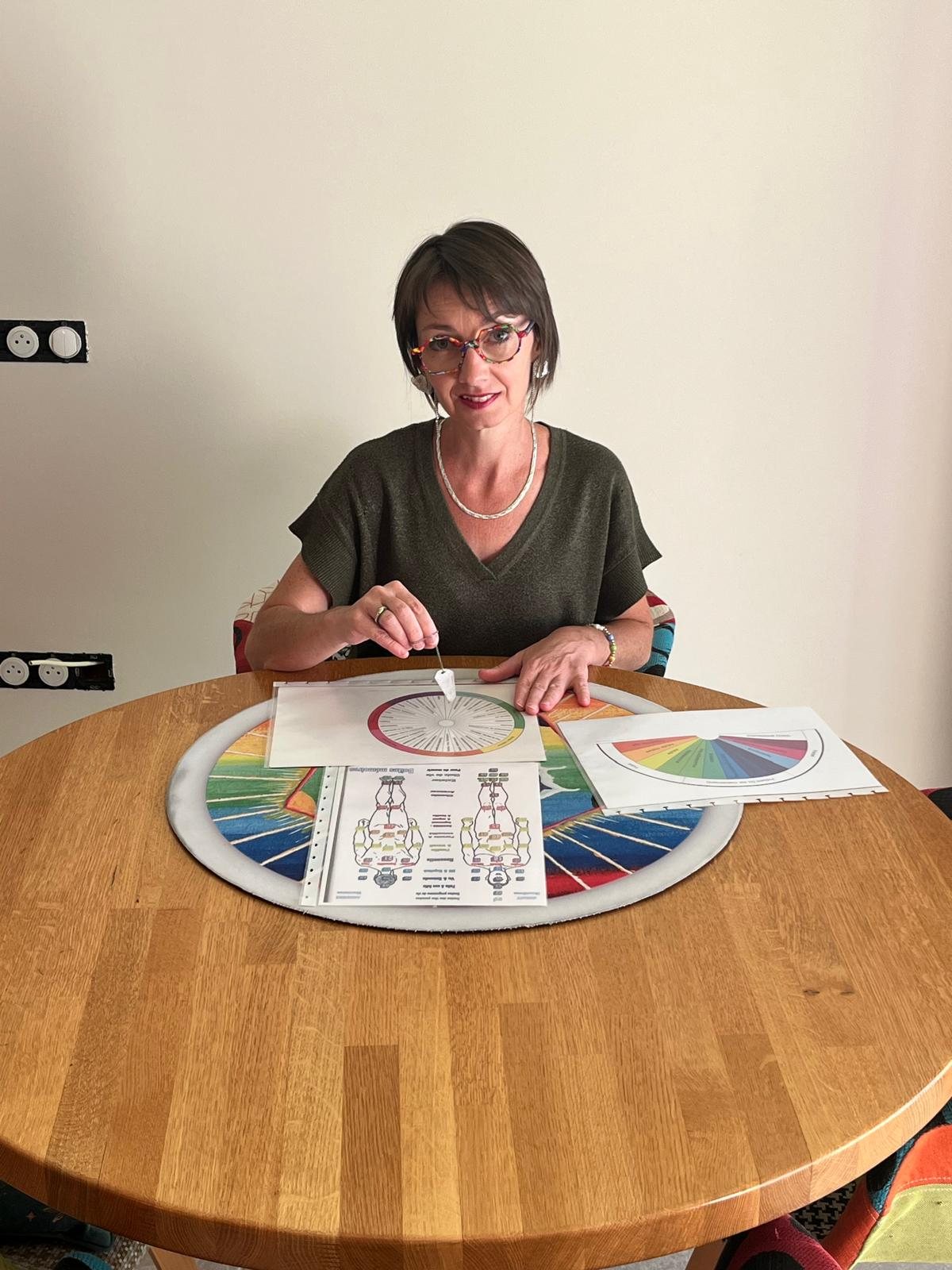 Émilie Haras tenant son jeu de cartes, assise à sa table
